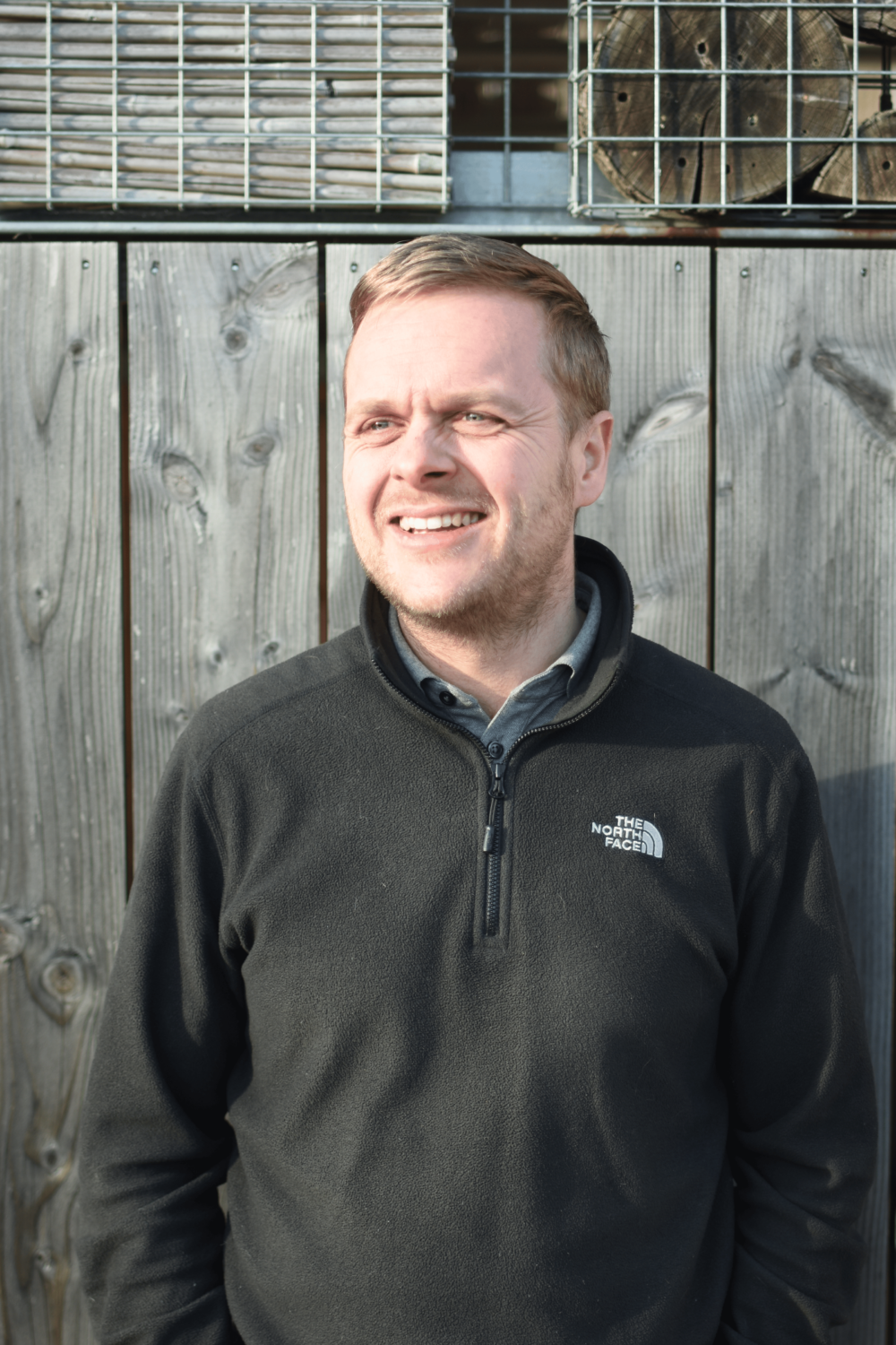 Technical Director smiles for a photo in front of an ecological green shelter
